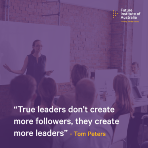 The quote reads, "True leaders don't create more followers, they create more leaders". The quote is against a translucent purple image of a classroom scenario, where change leadership is being taught. Quote is by Tom Peters.